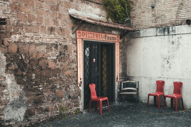 Ein Gebäude aus hellem Sandstein, über der Tür ein Schild mit der Aufschrift Pizzeria.