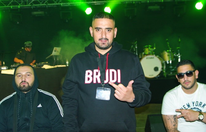 Haft·befehl in einem schwarzen Sweatshirt mit der Aufschrift Brudi. Er zeigt den ausgestreckten Mittelfinger in die Kamera.