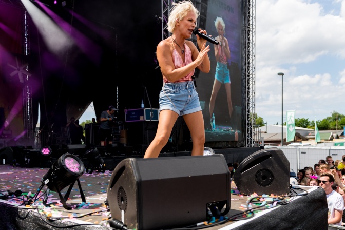 Michelle auf der Bühne in einer kurzen Jeansshorts. Sie singt in ein Mikrofon.