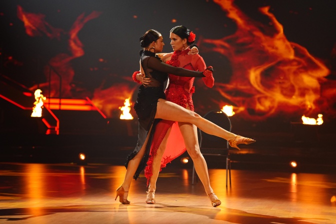 Vica Sauerwald und Vanessa Borck tanzen Tango miteinander, die Bühne ist rot beleuchtet.