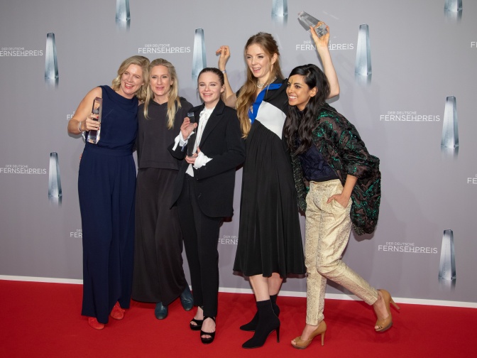 Eine Gruppe von 5 Schauspielerinnen mit Preisskulpturen aus Plexiglas steht vor einer Logoand des Fernsehpreises.
