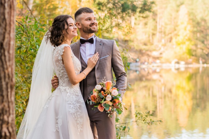 Ein Hochzeitspaar in Anzug und Brautkleid vor einem Teich