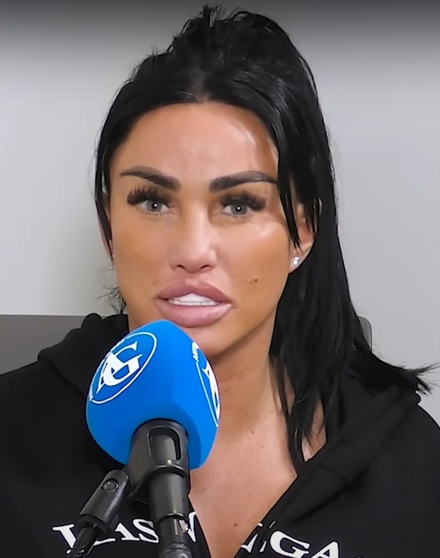 Katie Price spricht in ein Mikro. Sie hat dunkle, zum Pferdeschwanz gebundene Haare, in ihrem Gesicht sieht man Spuren vieler Schönheitsoperationen.
