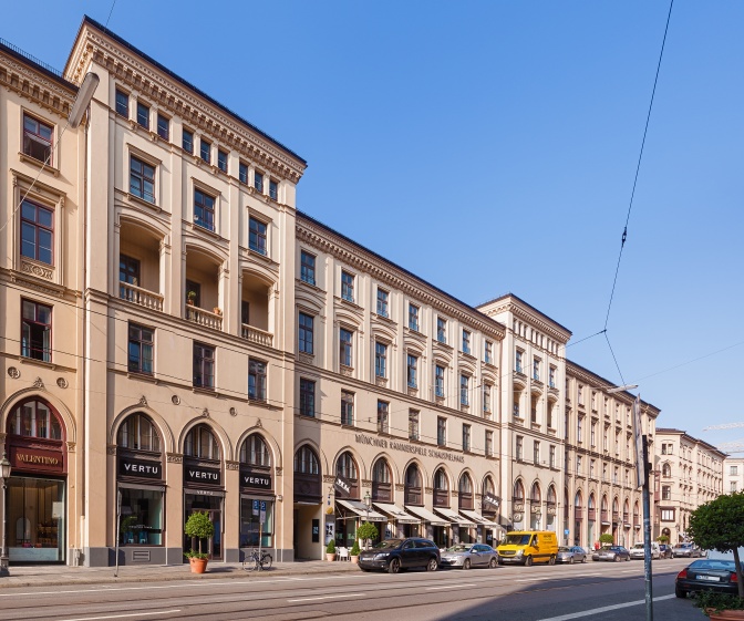 Ein helles, mehrgeschossiges Gebäude an der Straße.