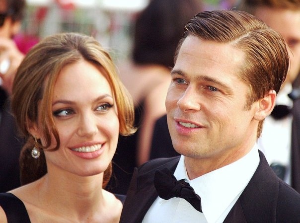 Angelina Jolie und Brad Pitt in festlicher Kleidung. Sie trägt ein schwarzes Kleid, er Anzug und Fliege. Beide lächeln.