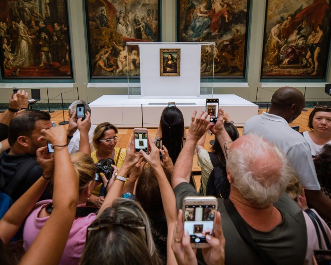 Eine große Menschentraube steht im Museum und fotografiert ein Gemälde mit dem Smartphone.