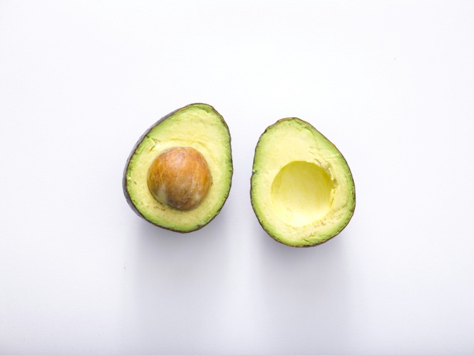 Eine aufgeschnittene Avocado, in einer Hälfte steckt noch der Kern.