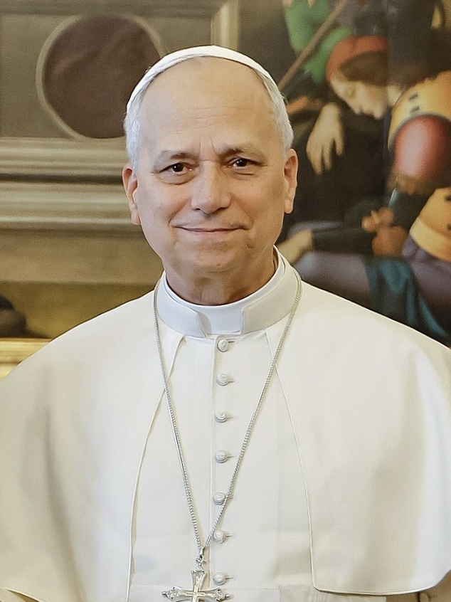 Papst Leo in weißer Kleidung mit einer weißen Kappe auf dem Kopf. Er hat ein großes Kreuz um den Hals hängen und schaut direkt in die Kamera.