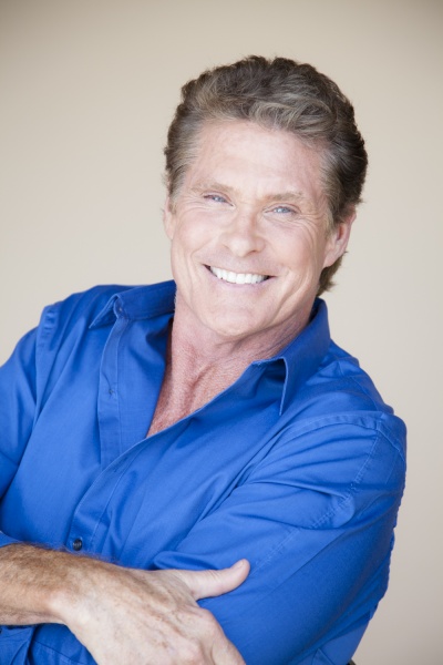David Hasselhoff verschränkt die Arme vor dem Oberkörper und lehnt sich zurück. Er trägt ein auffälliges blaues Hemd.