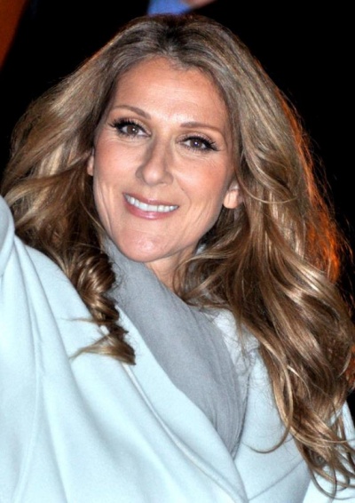 Céline Dion lächelt. Sie hat lange, gewellte Haare.