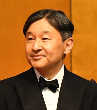 Kaiser Naruhito mit glatten, zum Mittelscheitel frisierten schwarzen Haaren und in Anzug und Fliege. Er lächelt leicht.