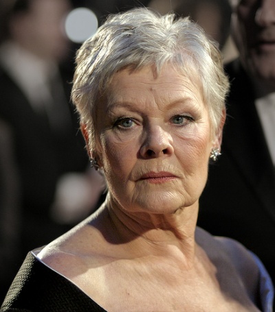Judi Dench mit kurzen grauen Haaren in einem dunklen Kleid mit tiefem Ausschnitt