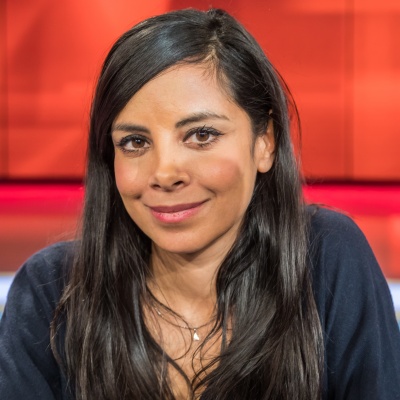 Collien Ulmen-Fernandes mit langen, glatten dunklen Haaren. Sie lächelt und trägt eine schwarze Bluse.