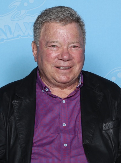 William Shatner lächelnd in Hemd und Sakko.