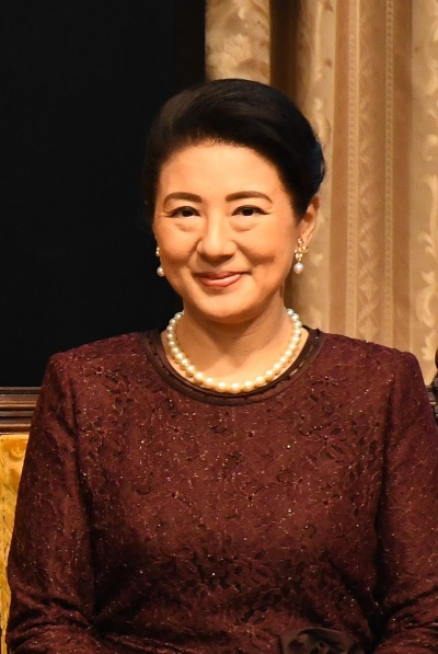Kaiserin Masako mit hochgesteckten schwarzen Haaren. Sie trägt ein festliches, besticktes Kleid und Perleenschmuck.