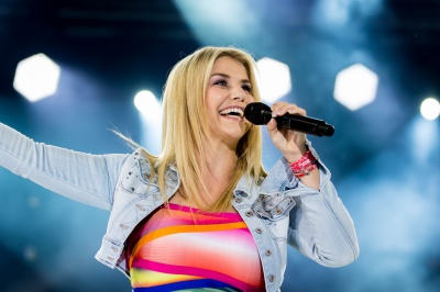 Beatrice Egli singt in ein Mikrophon, Scheinwerfer im Hintergrund